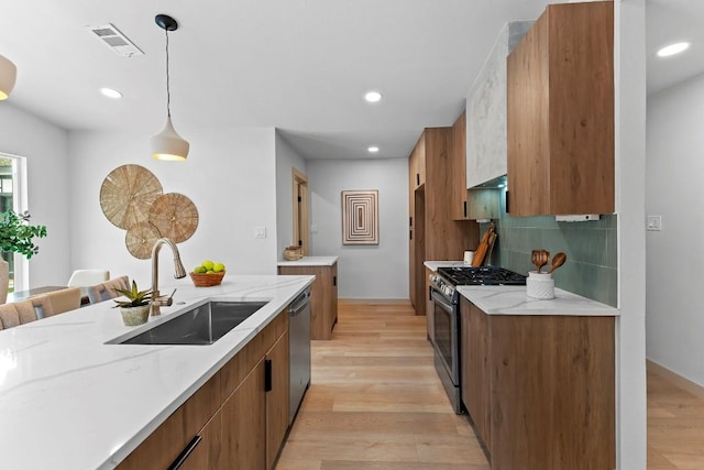 kitchen with sink, stainless steel appliances, tasteful backsplash, light hardwood / wood-style floors, and decorative light fixtures