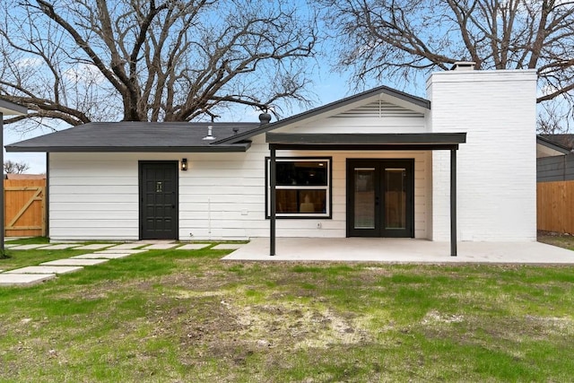 back of property with a yard and a patio area