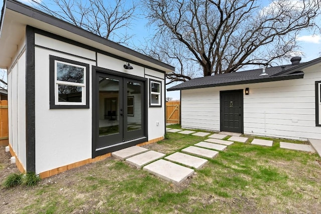 back of house featuring a yard, an outbuilding, and french doors