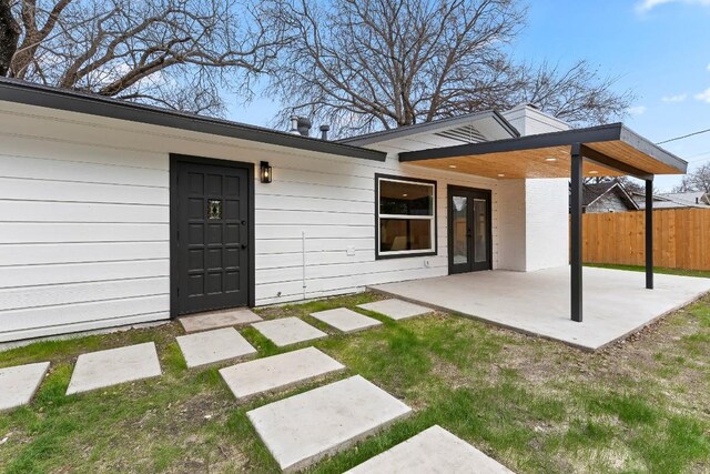 back of property with a lawn and a patio