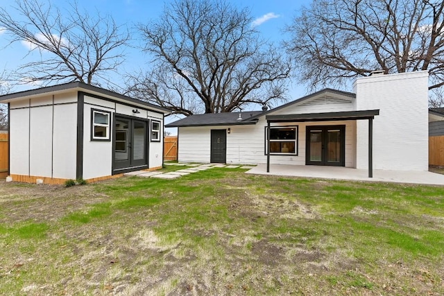 rear view of property with an outbuilding, a lawn, and a patio