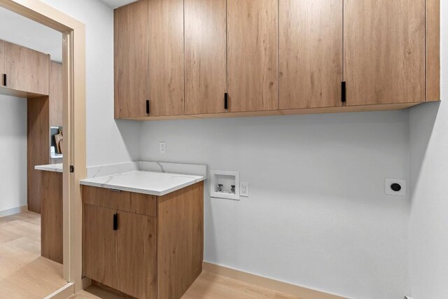 clothes washing area featuring cabinets, washer hookup, light hardwood / wood-style flooring, and electric dryer hookup