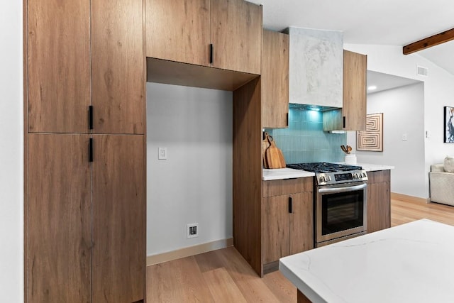 kitchen with lofted ceiling with beams, light hardwood / wood-style floors, decorative backsplash, and stainless steel gas range oven