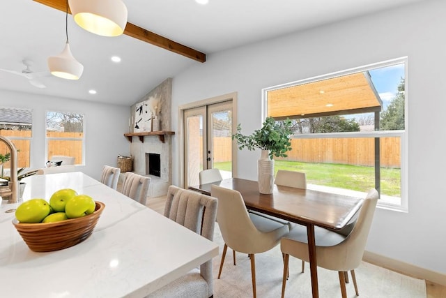 dining room featuring a fireplace, plenty of natural light, and lofted ceiling with beams