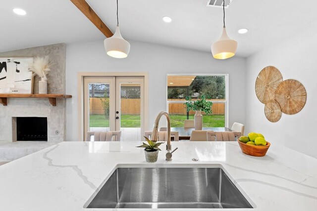 kitchen with french doors, light stone countertops, sink, and hanging light fixtures