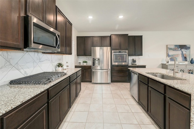 kitchen with tasteful backsplash, appliances with stainless steel finishes, sink, and dark brown cabinetry