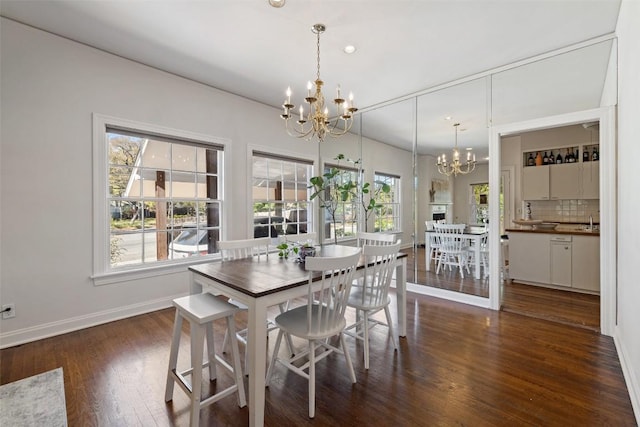 dining space with dark wood-type flooring, a wealth of natural light, and a notable chandelier