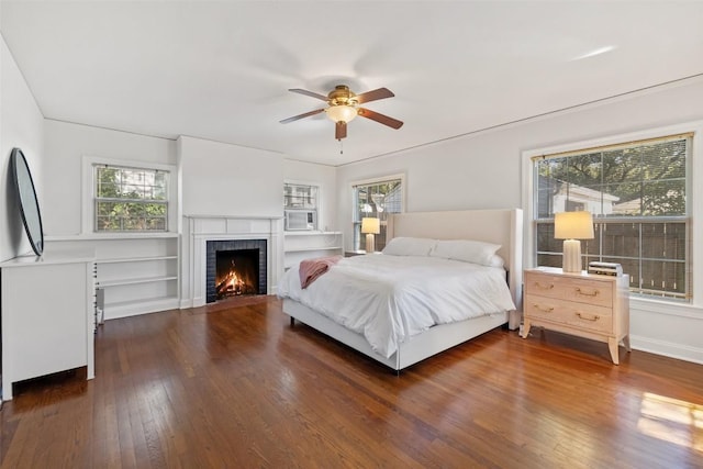 bedroom with dark wood-type flooring, a brick fireplace, and multiple windows