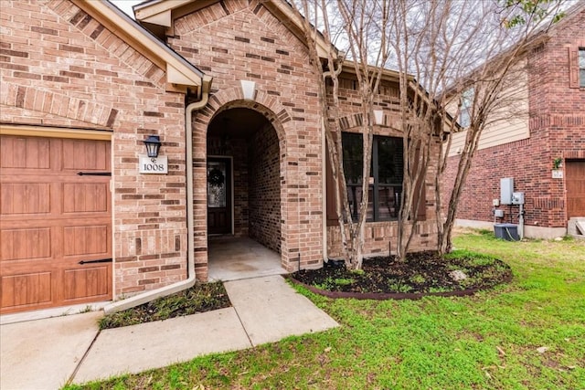 view of exterior entry featuring a garage and a lawn