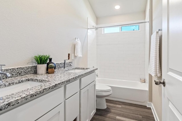 full bathroom featuring hardwood / wood-style flooring, tiled shower / bath, vanity, and toilet