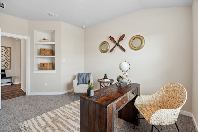 sitting room featuring lofted ceiling, built in shelves, and carpet