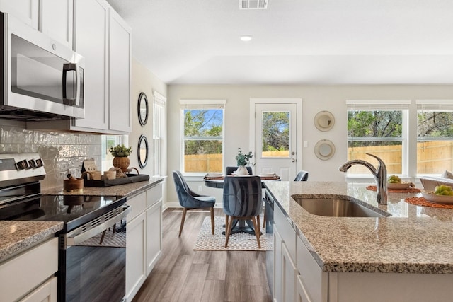 kitchen featuring white cabinetry, appliances with stainless steel finishes, sink, and light stone counters