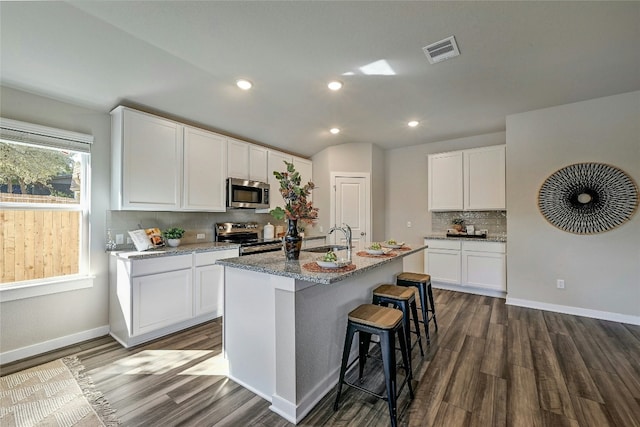 kitchen featuring a center island with sink, appliances with stainless steel finishes, sink, light stone counters, and white cabinets