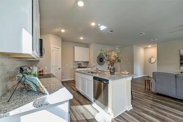 kitchen featuring appliances with stainless steel finishes, light stone countertops, white cabinets, sink, and a kitchen island with sink