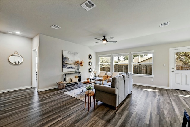 living room featuring ceiling fan, dark wood-type flooring, and a textured ceiling