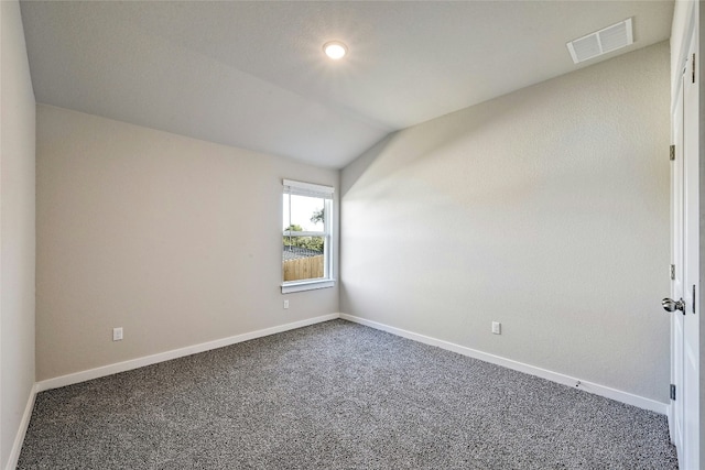 spare room with dark colored carpet and lofted ceiling