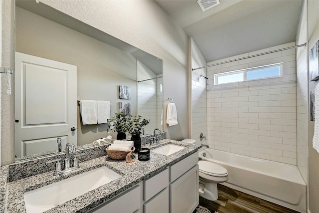 full bathroom with hardwood / wood-style floors, toilet, vanity, and tiled shower / bath combo