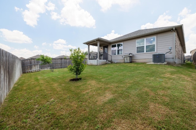 rear view of property featuring cooling unit and a lawn