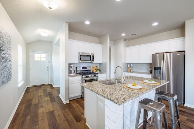 kitchen with sink, stainless steel appliances, white cabinets, and a center island with sink