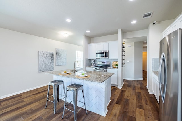 kitchen featuring sink, a breakfast bar area, white cabinetry, an island with sink, and stainless steel appliances