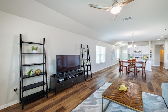 living room with dark wood-type flooring and ceiling fan with notable chandelier