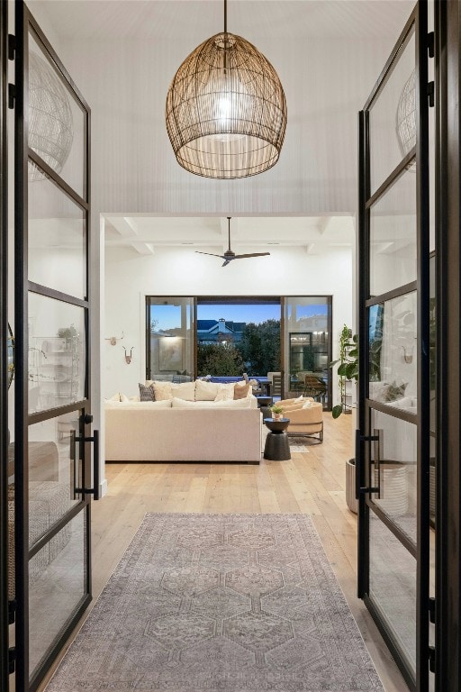 bedroom with hardwood / wood-style flooring, french doors, a chandelier, and a high ceiling