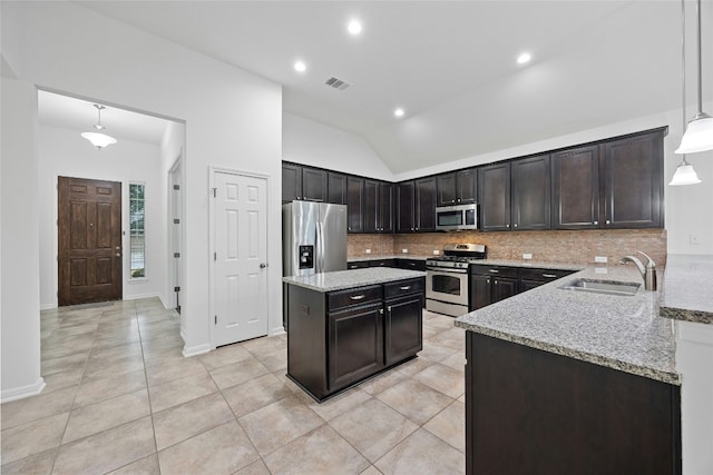 kitchen with appliances with stainless steel finishes, decorative light fixtures, sink, backsplash, and light stone countertops