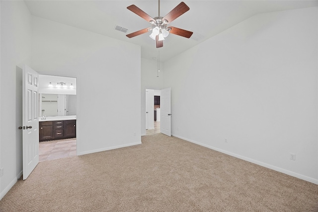 unfurnished bedroom with ceiling fan, ensuite bath, high vaulted ceiling, and light carpet