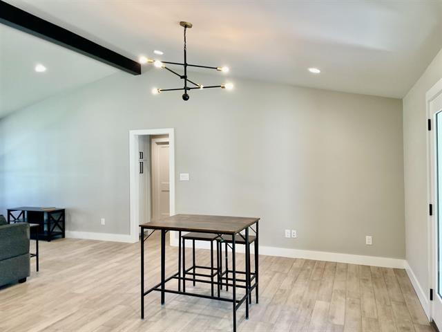 dining room with an inviting chandelier, lofted ceiling with beams, and light wood-type flooring