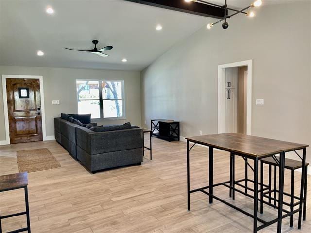 living room with lofted ceiling with beams, ceiling fan, and light wood-type flooring