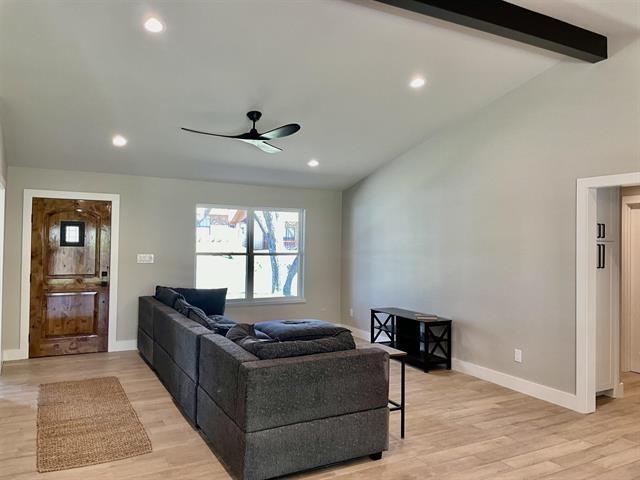 living room featuring ceiling fan, lofted ceiling with beams, and light hardwood / wood-style flooring