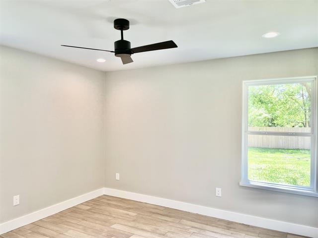 empty room with ceiling fan and light hardwood / wood-style flooring