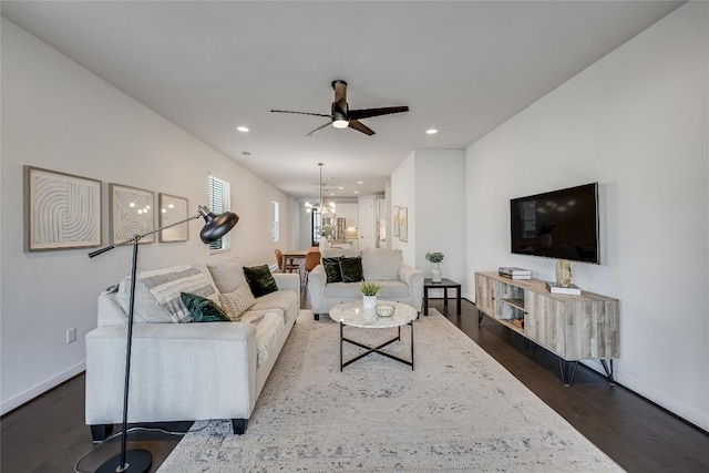 living room featuring dark wood-type flooring and ceiling fan with notable chandelier