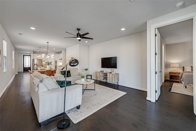 living room featuring ceiling fan with notable chandelier and dark hardwood / wood-style flooring