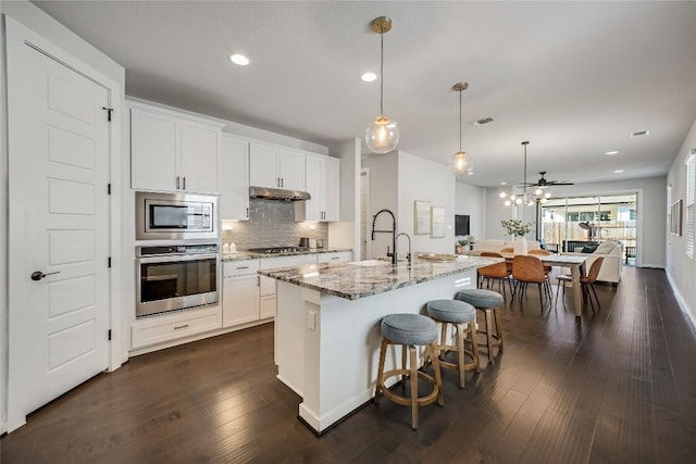 kitchen featuring pendant lighting, white cabinetry, an island with sink, and appliances with stainless steel finishes