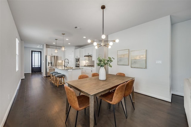 dining space featuring dark wood-type flooring, a chandelier, and sink