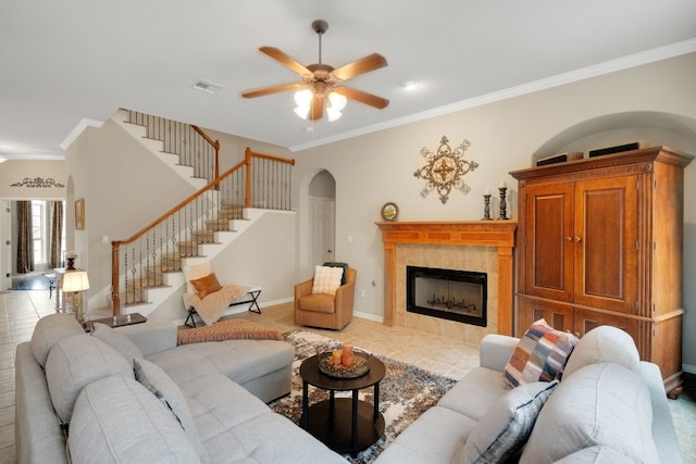 living room with a tile fireplace, ornamental molding, light tile patterned floors, and ceiling fan