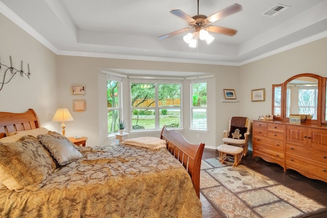 bedroom featuring crown molding, hardwood / wood-style floors, ceiling fan, and a tray ceiling