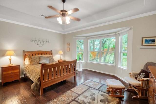 bedroom with dark hardwood / wood-style flooring, crown molding, a tray ceiling, and ceiling fan