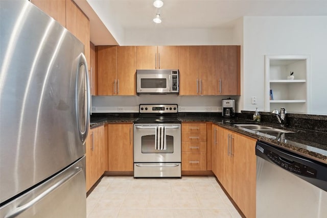 kitchen with dark stone countertops, sink, light tile patterned floors, and appliances with stainless steel finishes