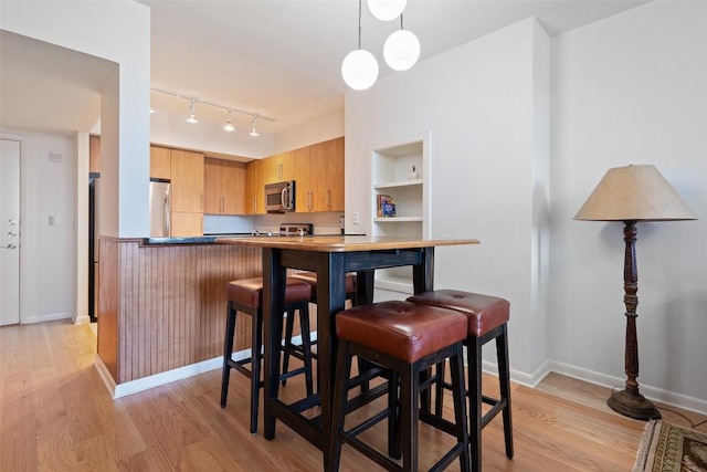 dining space with rail lighting and light wood-type flooring