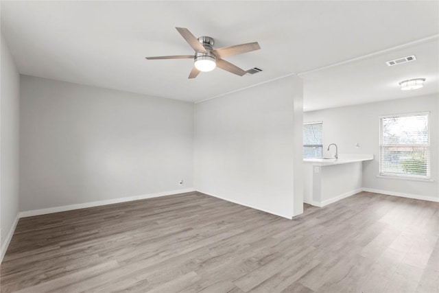 empty room featuring ceiling fan, sink, and light hardwood / wood-style flooring