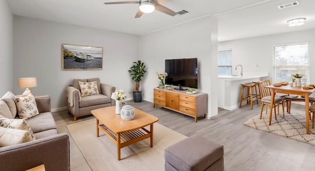 living room with ceiling fan, sink, and light hardwood / wood-style floors