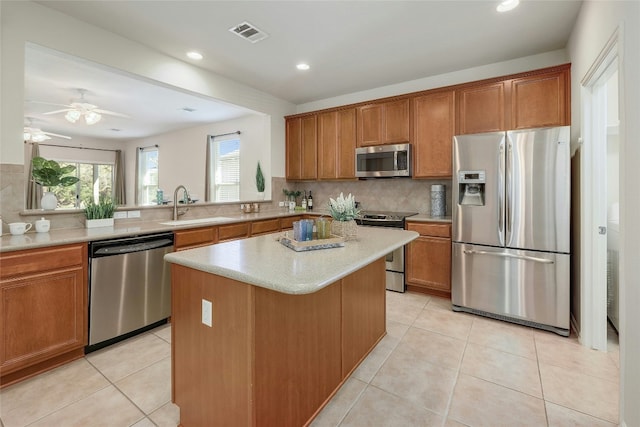 kitchen featuring sink, backsplash, stainless steel appliances, a center island, and kitchen peninsula