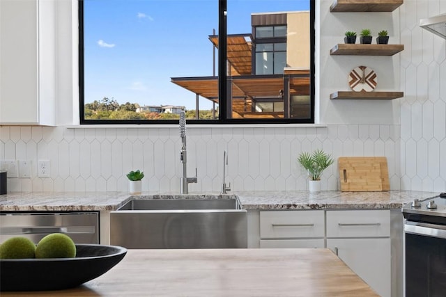 kitchen with sink, stainless steel appliances, white cabinets, and light stone countertops