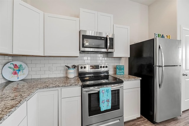 kitchen featuring light stone counters, appliances with stainless steel finishes, decorative backsplash, and white cabinets