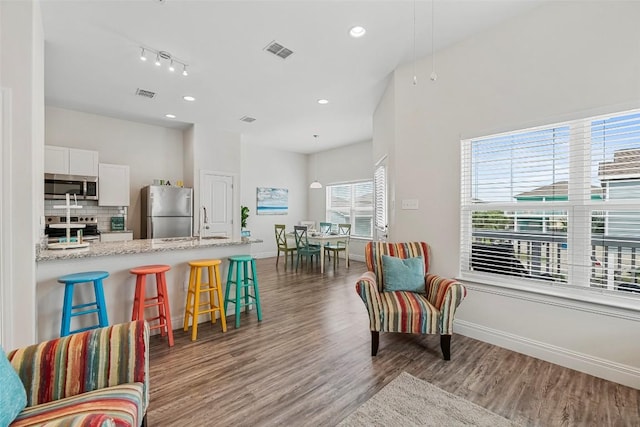 kitchen featuring appliances with stainless steel finishes, a breakfast bar, white cabinetry, backsplash, and light stone counters