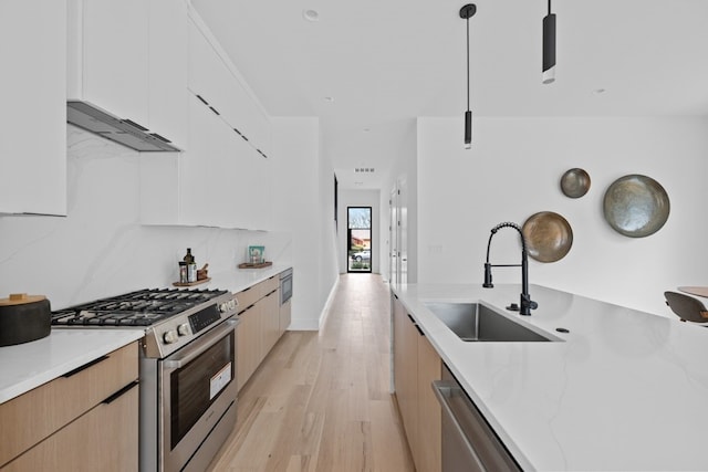 kitchen featuring pendant lighting, sink, appliances with stainless steel finishes, light stone counters, and white cabinets