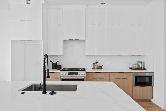 1409 Valleyridge Dr Unit B, Austin, TX 78704 - kitchen featuring stainless steel gas range oven, modern cabinets, light stone counters, light wood-type flooring, and white cabinetry