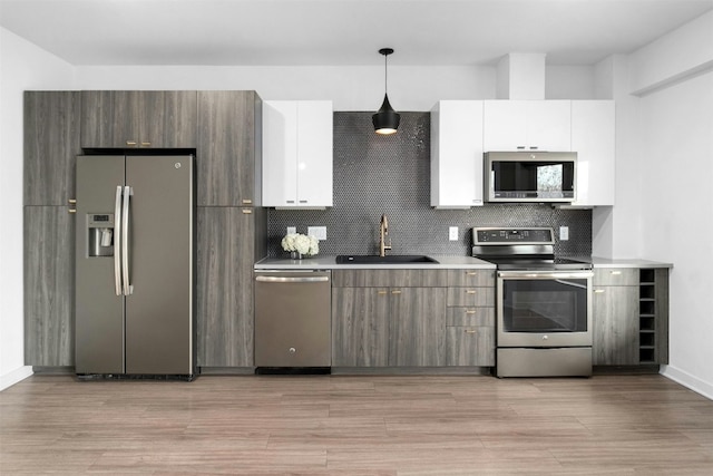 4361 S Congress Ave Unit 333, Austin, TX 78745 - kitchen with stainless steel appliances, white cabinetry, decorative backsplash, light wood-style flooring, and hanging light fixtures